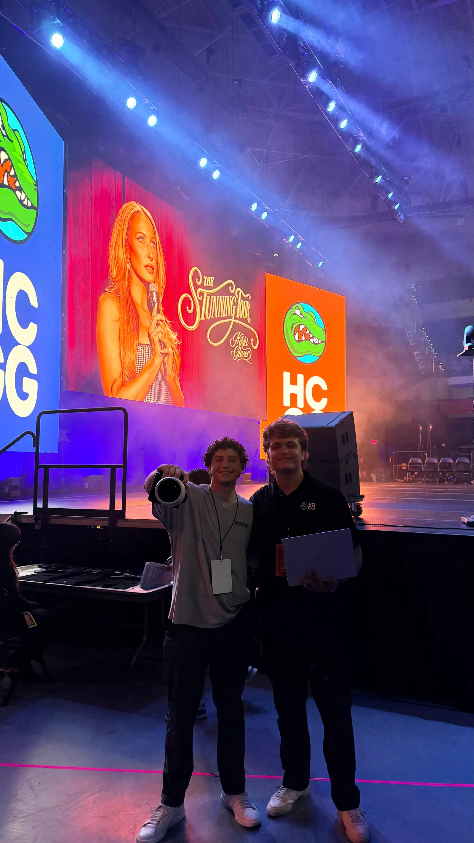 Jackson Kracht raises a camera beside a friend on the floor in front of the Homecoming and Gator Growl stage.